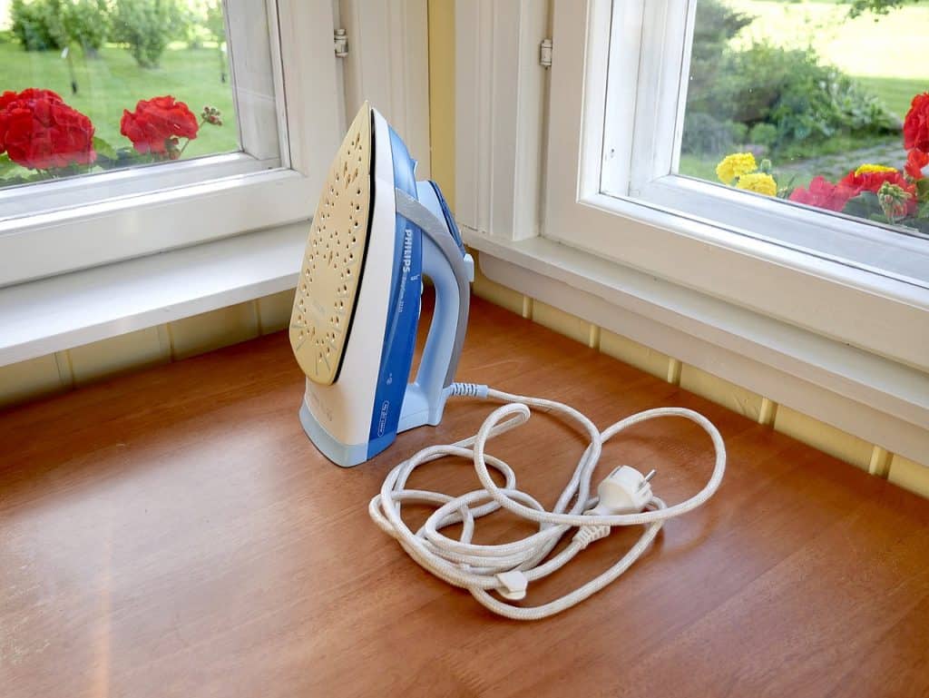 A steam iron on the floor with tangled cords